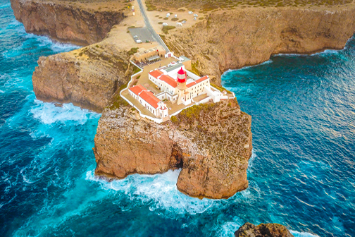 Cabo de São Vicente in de Algarve met steile rotskliffen, een vuurtoren en uitzicht over de uitgestrekte Atlantische Oceaan.